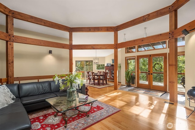 living room featuring an inviting chandelier, wood finished floors, visible vents, and french doors