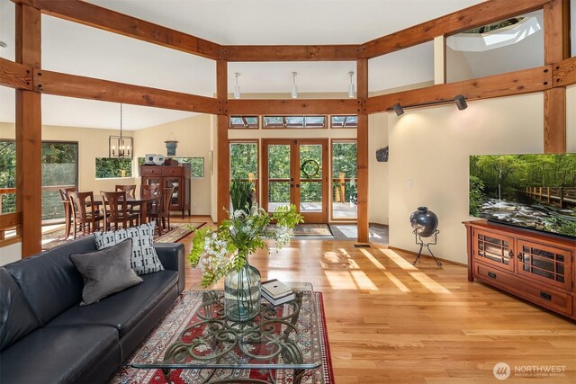 living room featuring a chandelier, light wood-style flooring, french doors, and lofted ceiling with beams