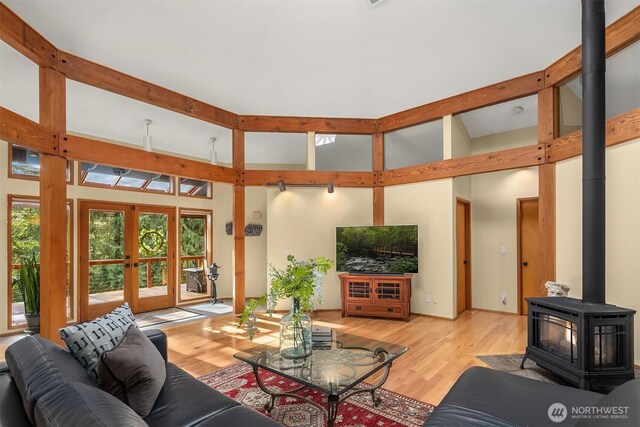 living room featuring beam ceiling, french doors, light wood-type flooring, and a wood stove