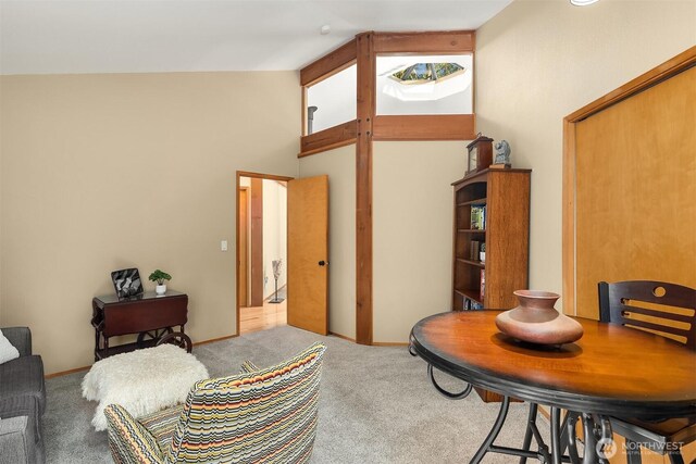 living area with high vaulted ceiling, baseboards, and carpet floors