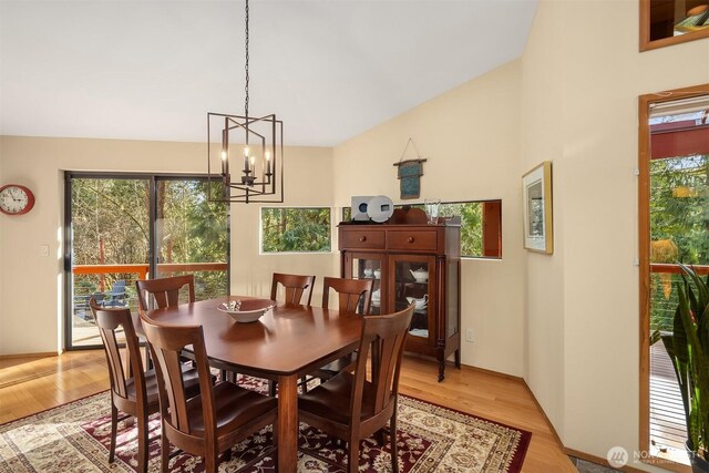 dining space featuring an inviting chandelier, light wood-style floors, and lofted ceiling