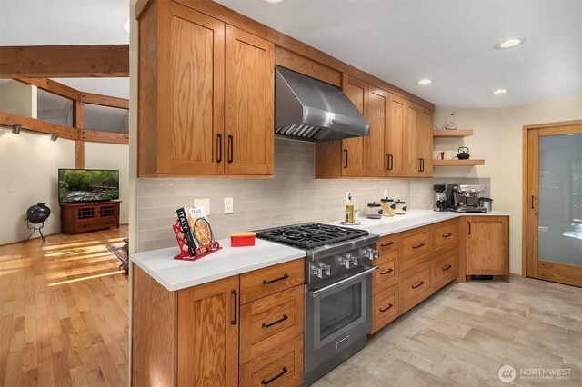 kitchen with backsplash, light countertops, stainless steel range, wall chimney exhaust hood, and open shelves