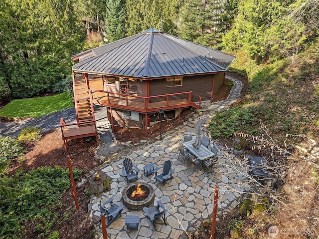 back of house featuring stairway, a wooden deck, a standing seam roof, a fire pit, and a patio area