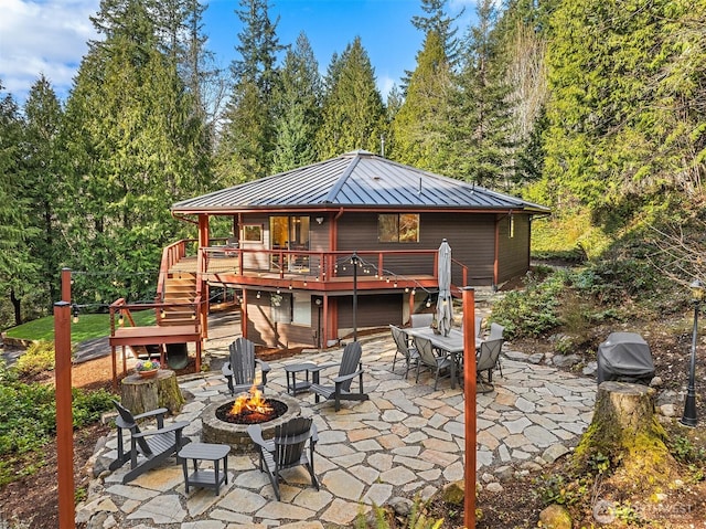 rear view of house featuring stairs, a patio, a standing seam roof, and an outdoor fire pit