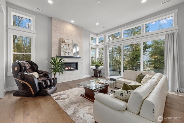 living room with a fireplace, visible vents, wood finished floors, and recessed lighting