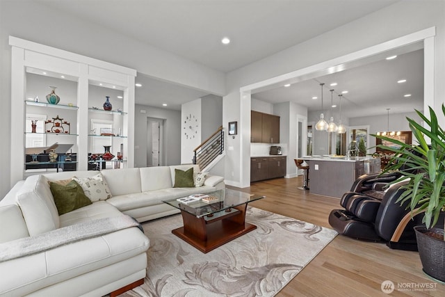 living room featuring a chandelier, stairway, light wood-style flooring, and recessed lighting