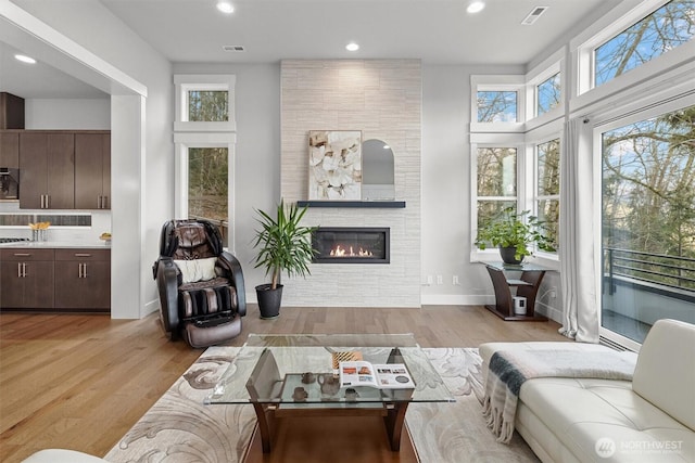 living area with recessed lighting, a fireplace, visible vents, baseboards, and light wood-type flooring