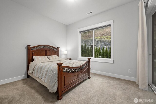 bedroom with baseboards, visible vents, and light colored carpet