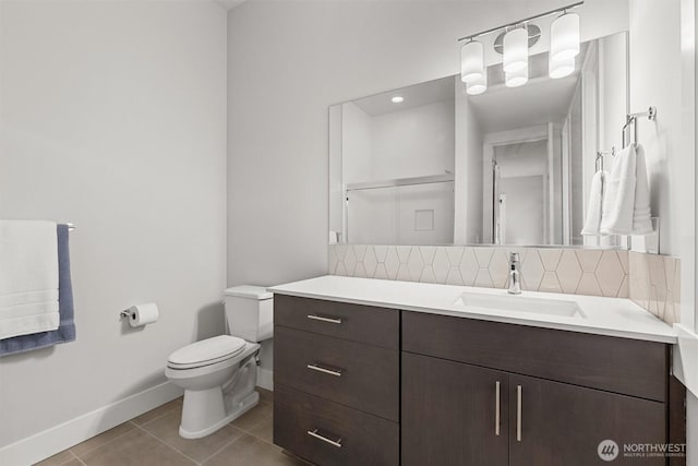 bathroom featuring tile patterned flooring, toilet, vanity, baseboards, and backsplash