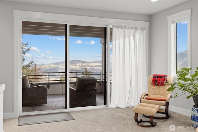 sitting room featuring carpet floors, plenty of natural light, baseboards, and a mountain view