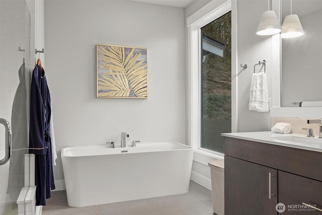 full bath with a shower stall, vanity, a freestanding tub, baseboards, and tile patterned floors