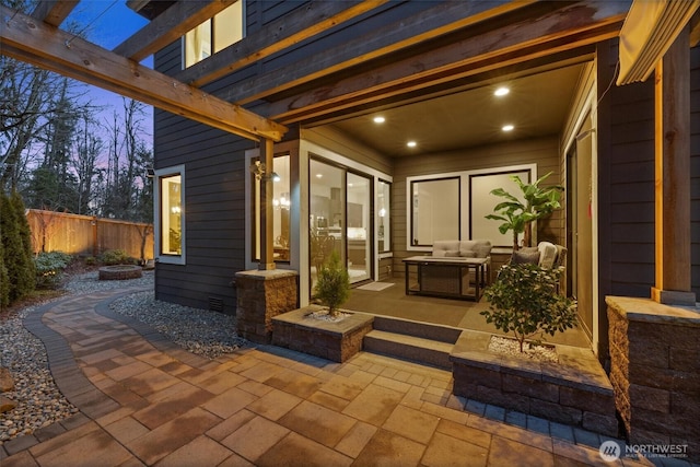 patio terrace at dusk with fence, an outdoor living space, and a pergola