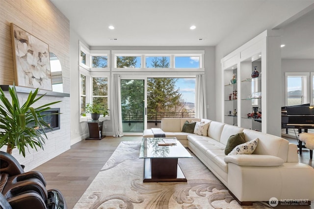 living room featuring plenty of natural light, a fireplace, wood finished floors, and recessed lighting