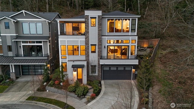 modern home with a garage, a standing seam roof, driveway, and stone siding