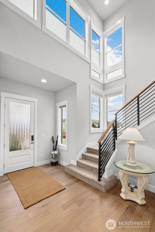 entryway with stairs, a high ceiling, wood finished floors, and a wealth of natural light