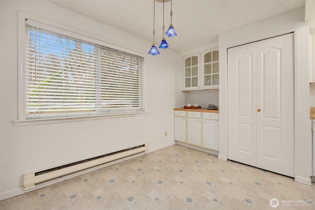 unfurnished dining area with light floors, a baseboard radiator, and baseboards