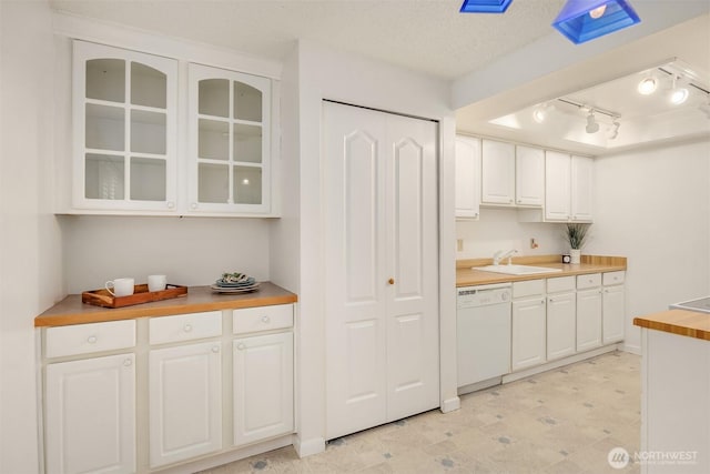 kitchen with glass insert cabinets, white cabinets, a sink, a textured ceiling, and dishwasher