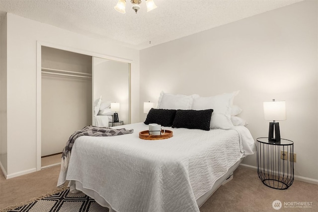 bedroom featuring carpet, a closet, a textured ceiling, and baseboards