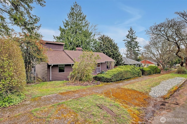 view of side of home with a lawn and a chimney