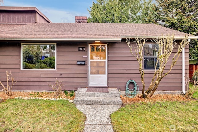 view of front of property with a front lawn and a shingled roof