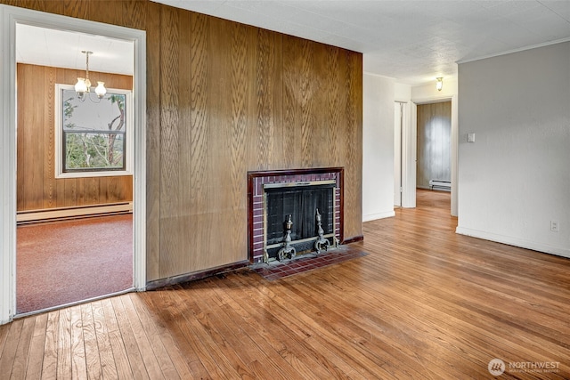 unfurnished living room featuring baseboard heating, an inviting chandelier, a fireplace with flush hearth, and hardwood / wood-style floors