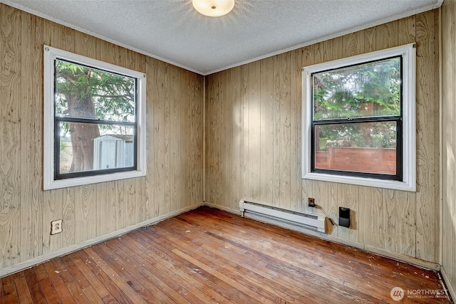 unfurnished room featuring a baseboard heating unit, wood-type flooring, a textured ceiling, and baseboards