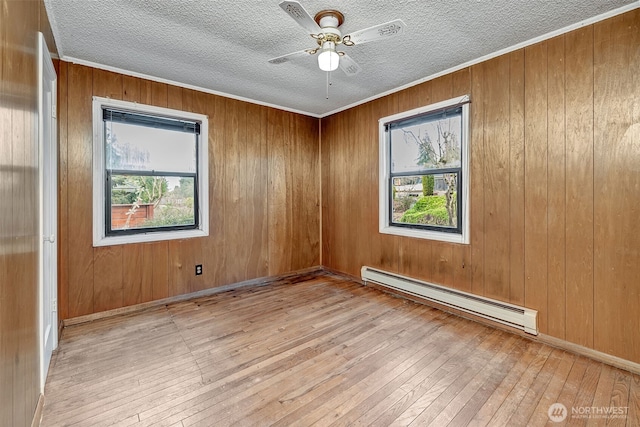 empty room featuring a baseboard heating unit, wood-type flooring, and a textured ceiling