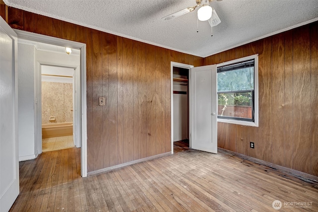 unfurnished bedroom featuring hardwood / wood-style flooring, wooden walls, a closet, and a textured ceiling