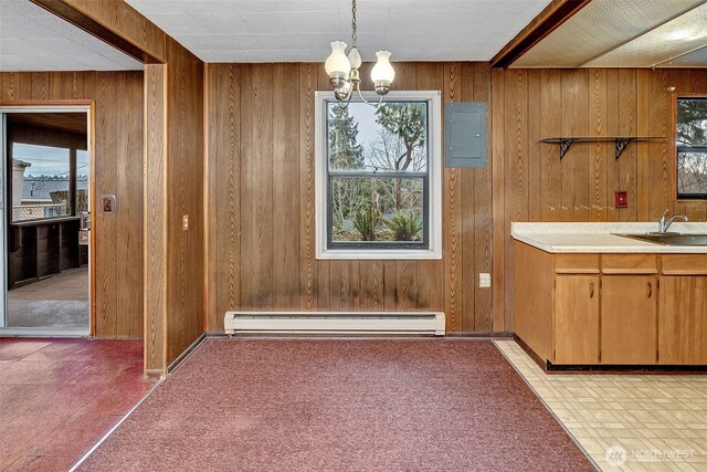 unfurnished dining area featuring wooden walls, a baseboard heating unit, electric panel, an inviting chandelier, and a sink