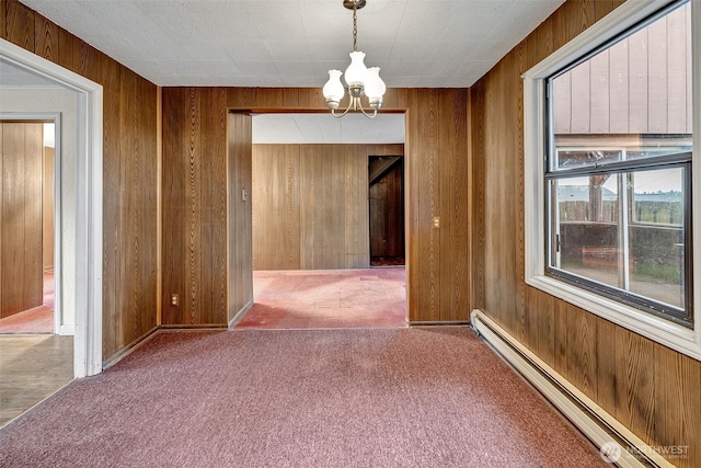 unfurnished dining area with an inviting chandelier, wooden walls, baseboard heating, and carpet floors