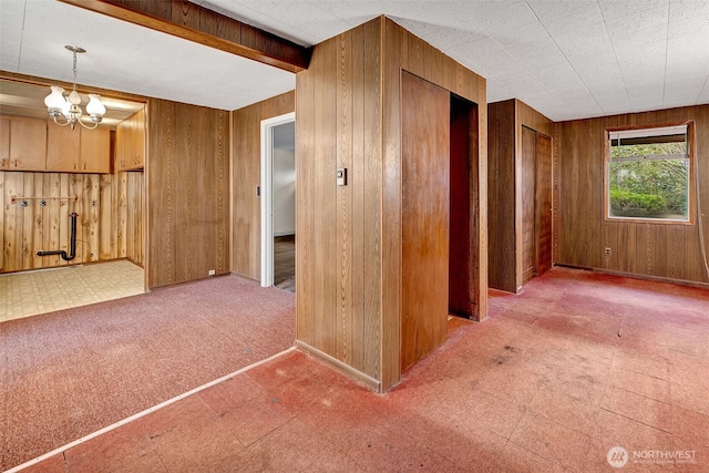 hallway with a notable chandelier, carpet floors, and wooden walls