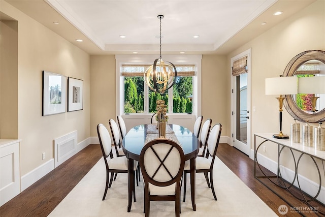 dining space with baseboards, a tray ceiling, recessed lighting, an inviting chandelier, and wood finished floors