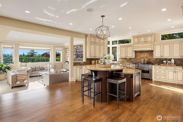 kitchen featuring an island with sink, cream cabinetry, and high end stainless steel range