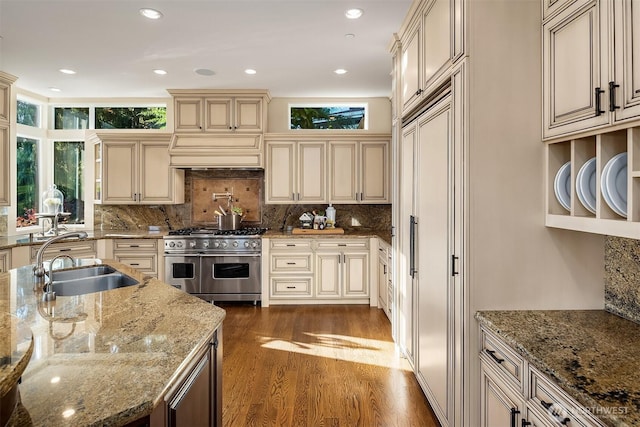 kitchen with dark wood-style floors, premium appliances, cream cabinets, and a sink