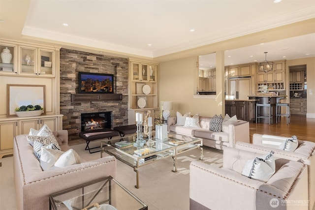 living area with a raised ceiling, recessed lighting, a fireplace, and wood finished floors