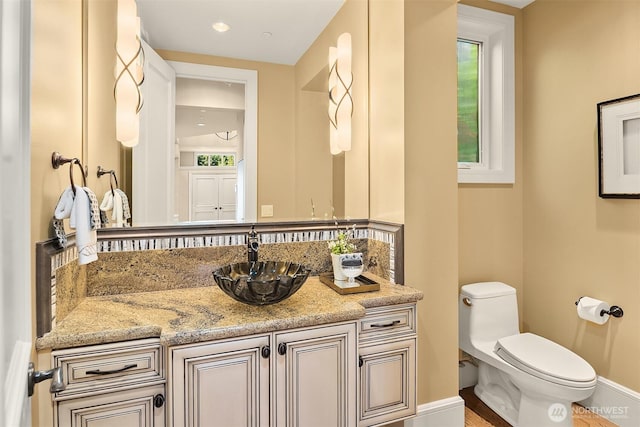 bathroom with toilet, vanity, and baseboards