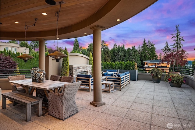 patio terrace at dusk featuring an outdoor living space with a fireplace and outdoor dining space