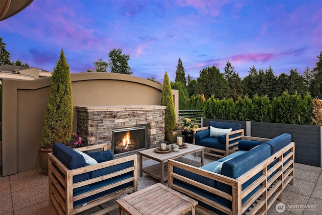 patio terrace at dusk with an outdoor living space with a fireplace