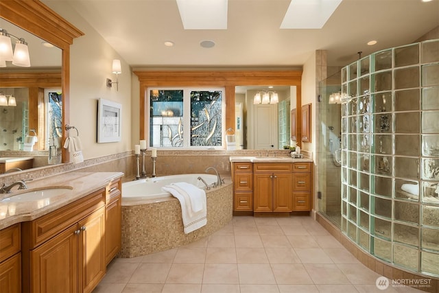 full bath featuring a skylight, a sink, a shower stall, a garden tub, and tile patterned floors