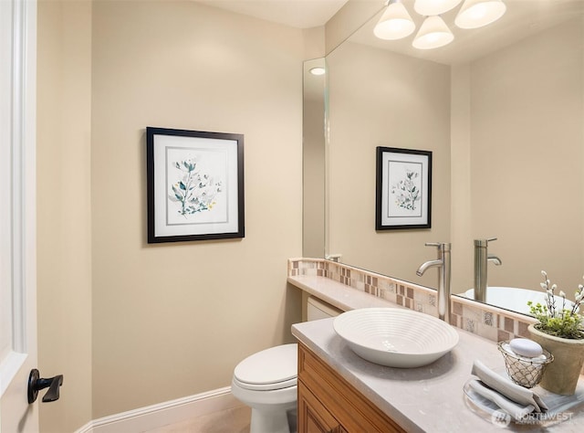 half bathroom with baseboards, toilet, and vanity