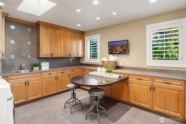 kitchen featuring light tile patterned floors, a skylight, recessed lighting, a sink, and tasteful backsplash