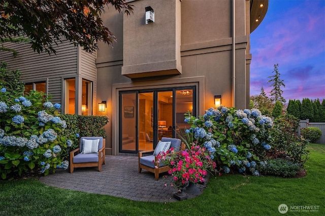 back of property featuring a patio, a lawn, and stucco siding