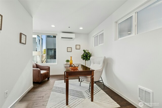 office space with recessed lighting, visible vents, wood finished floors, a wall mounted air conditioner, and baseboards