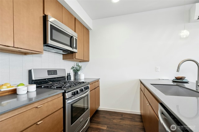 kitchen featuring a sink, baseboards, appliances with stainless steel finishes, backsplash, and dark wood finished floors