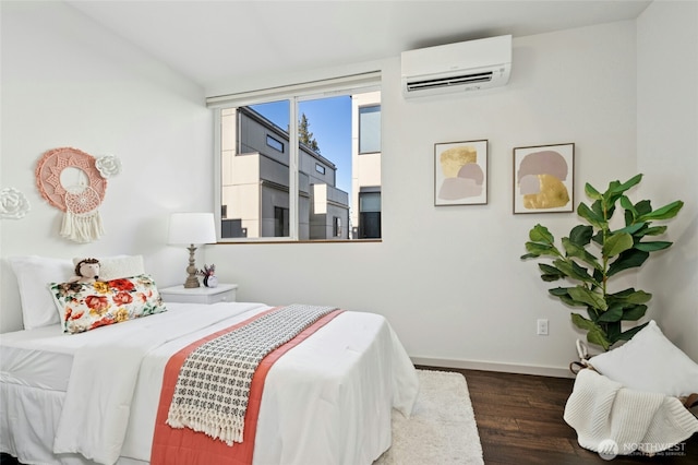 bedroom with baseboards, wood finished floors, and a wall mounted AC