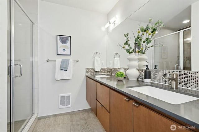 full bathroom with double vanity, a stall shower, visible vents, and a sink