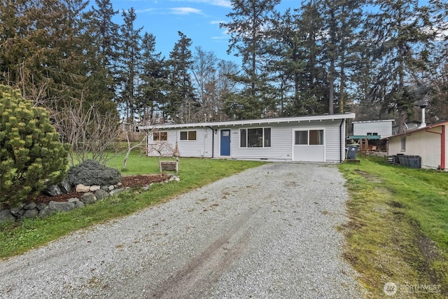 view of front of property featuring gravel driveway and a front lawn