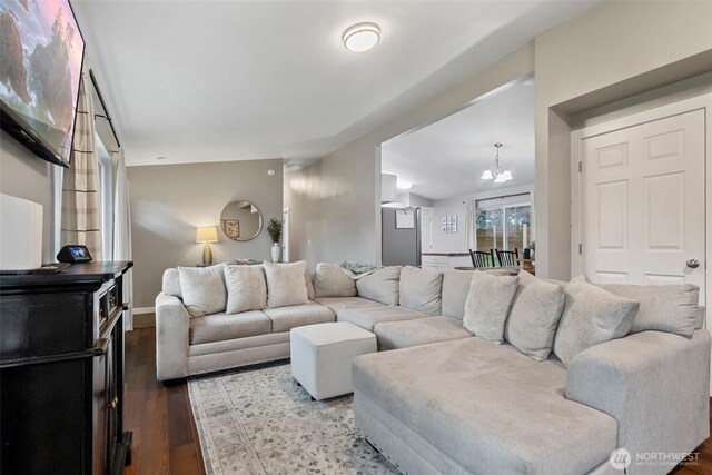 living room with a notable chandelier, baseboards, and wood finished floors