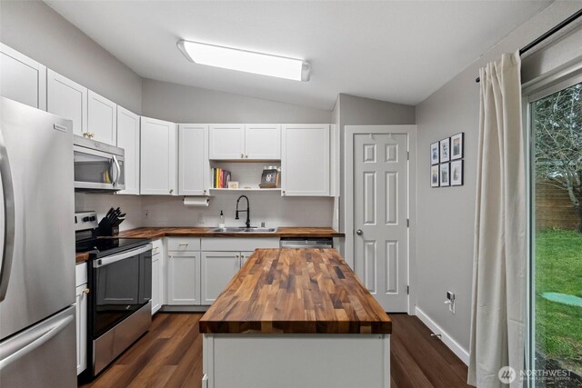 kitchen featuring lofted ceiling, stainless steel appliances, a sink, wooden counters, and decorative backsplash