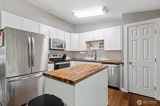 kitchen featuring stainless steel appliances, a sink, wooden counters, and white cabinetry